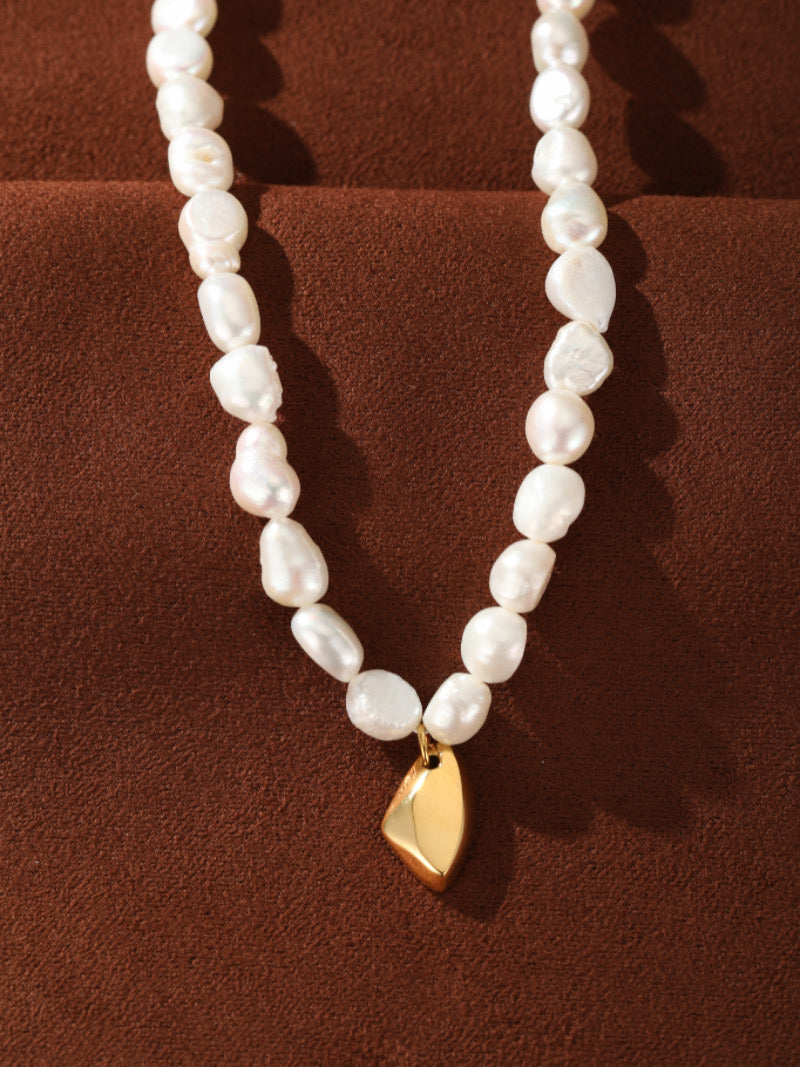 Collier Lyrical présentant un fil de perles blanches irrégulières d'eau douce avec un pendentif goutte abstrait lisse ton or.