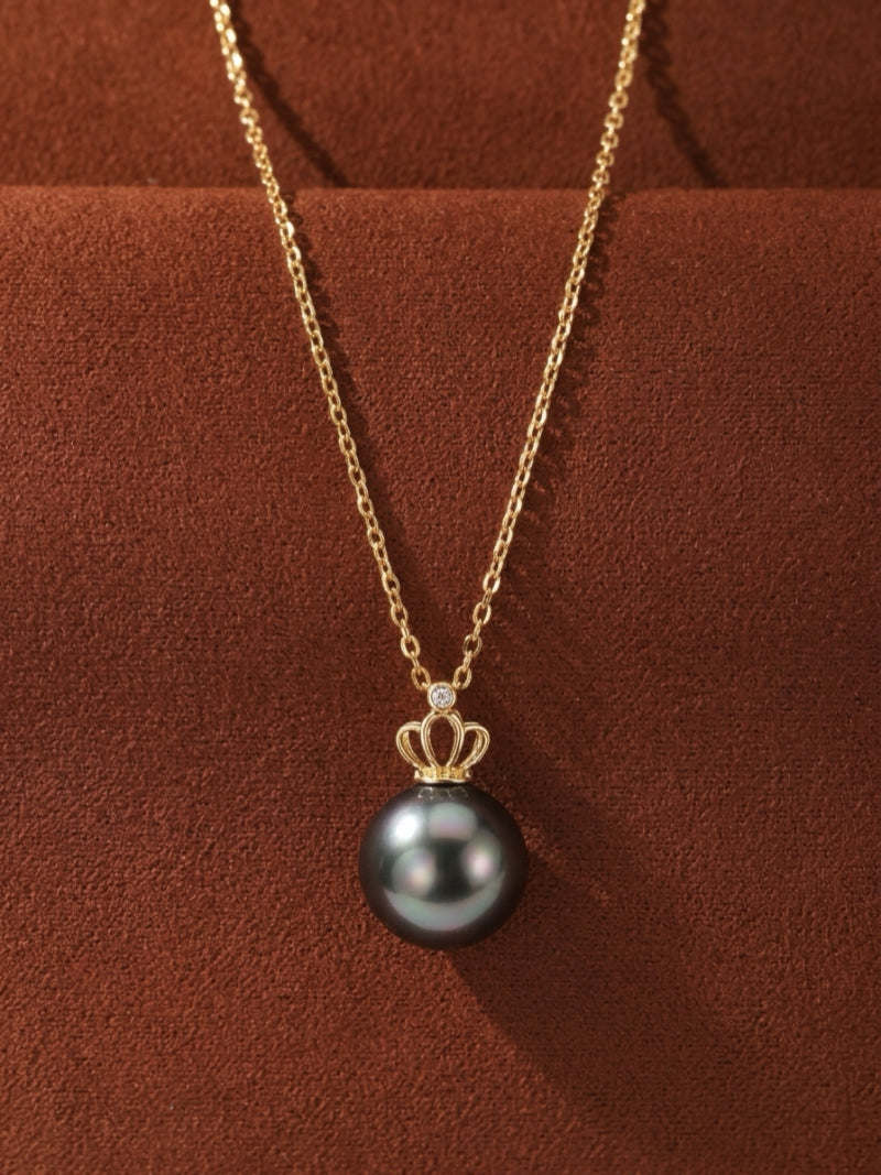 Majesty Tahitian pearl crown pendant necklace featuring a 9mm round Tahitian pearl with iridescent luster, crowned with a gold motif and a small diamond, suspended on a delicate gold chain.