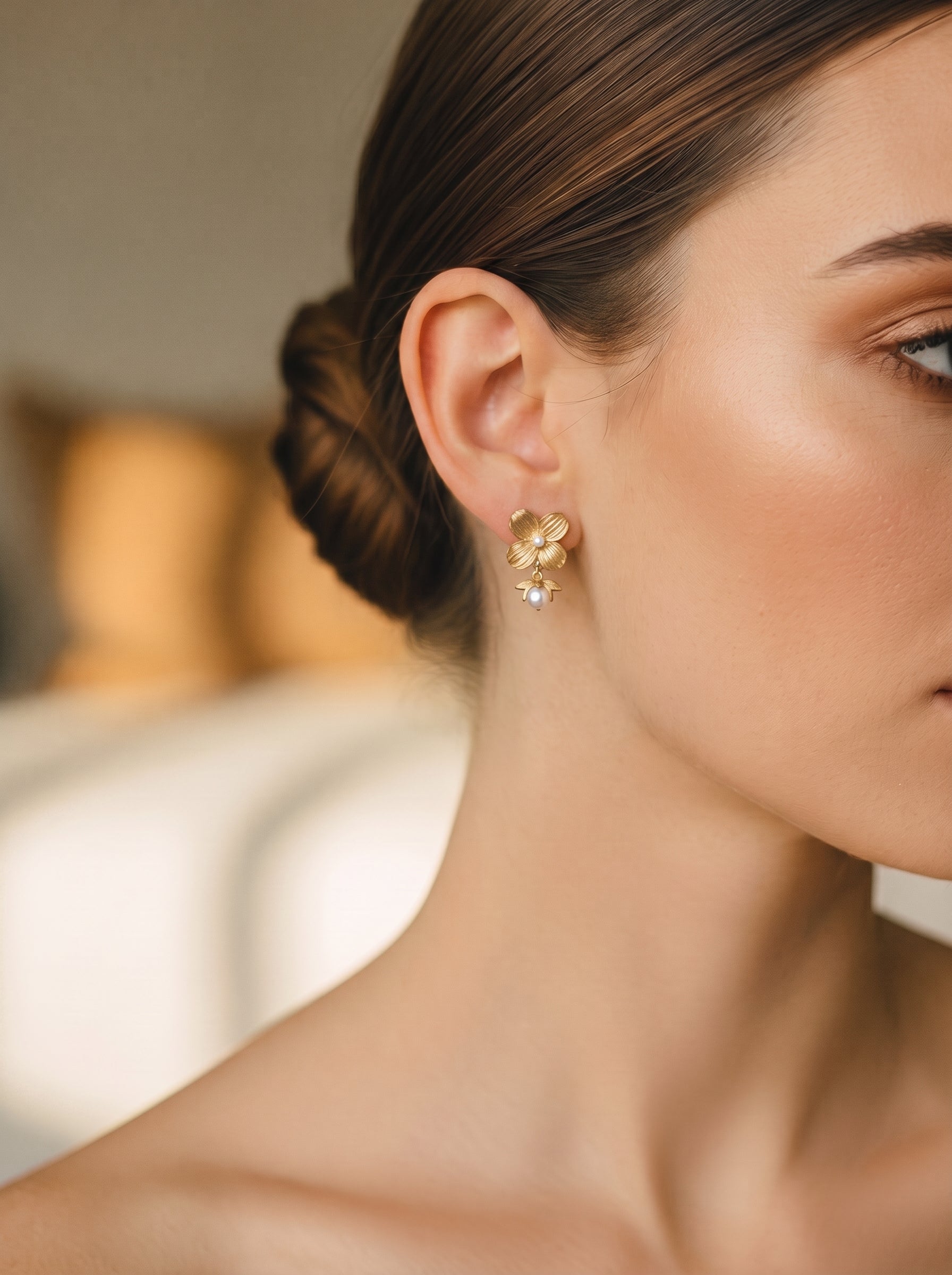 Boucles d'oreilles goutte florales ton or avec de petites perles à l'oreille d'une mannequin @model