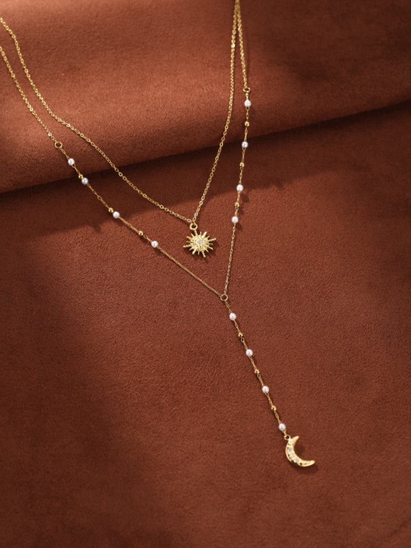 Nova layered necklace featuring delicate gold chains, small white freshwater pearls, a sparkling sun pendant, and a crescent moon charm.