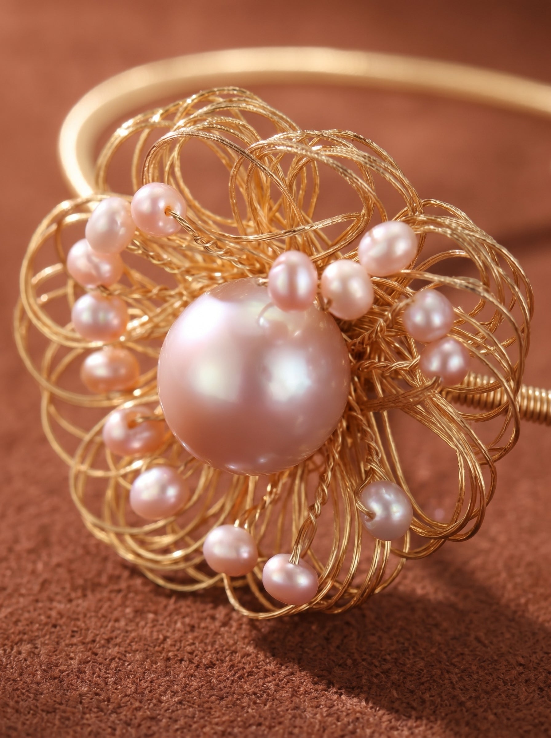 Gold-tone wire cuff bracelet with a flower design, featuring a large pink freshwater pearl at the center and smaller pink seed pearls around it. @pearl