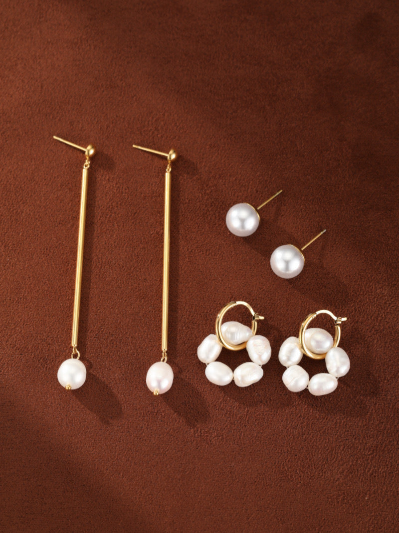 Une collection de quatre paires de boucles d'oreilles ton or, incluant deux délicates boucles d'oreilles pendantes avec des perles uniques, et deux créoles ornées de multiples perles baroques d'eau douce.