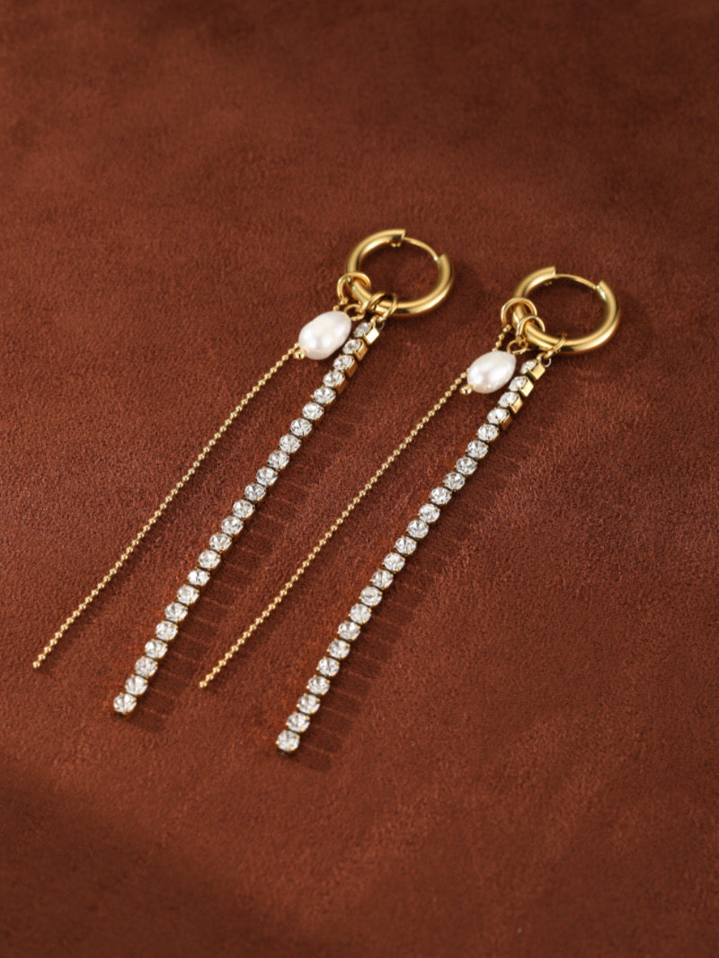 Gold-toned hoop earrings featuring a white freshwater pearl and a dangling line of clear crystals, with a delicate gold chain accent.