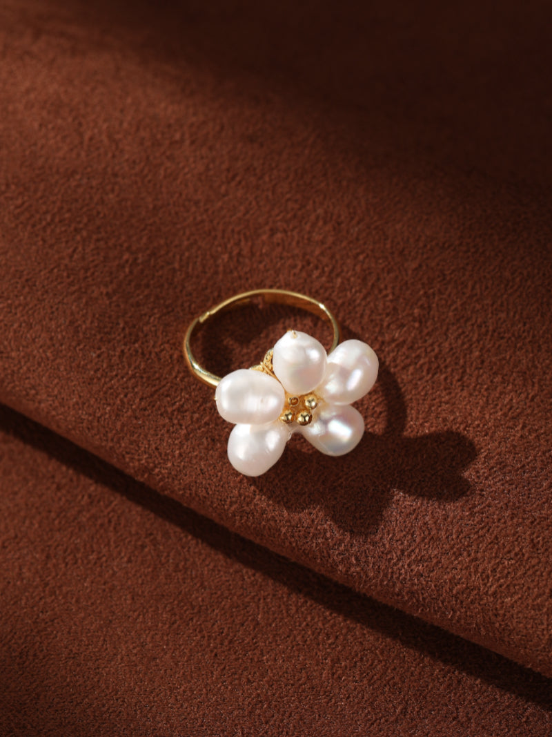 Radiance freshwater pearl flower cuff ring with five baroque pearls on a gold band, set against a textured brown background. @pearl