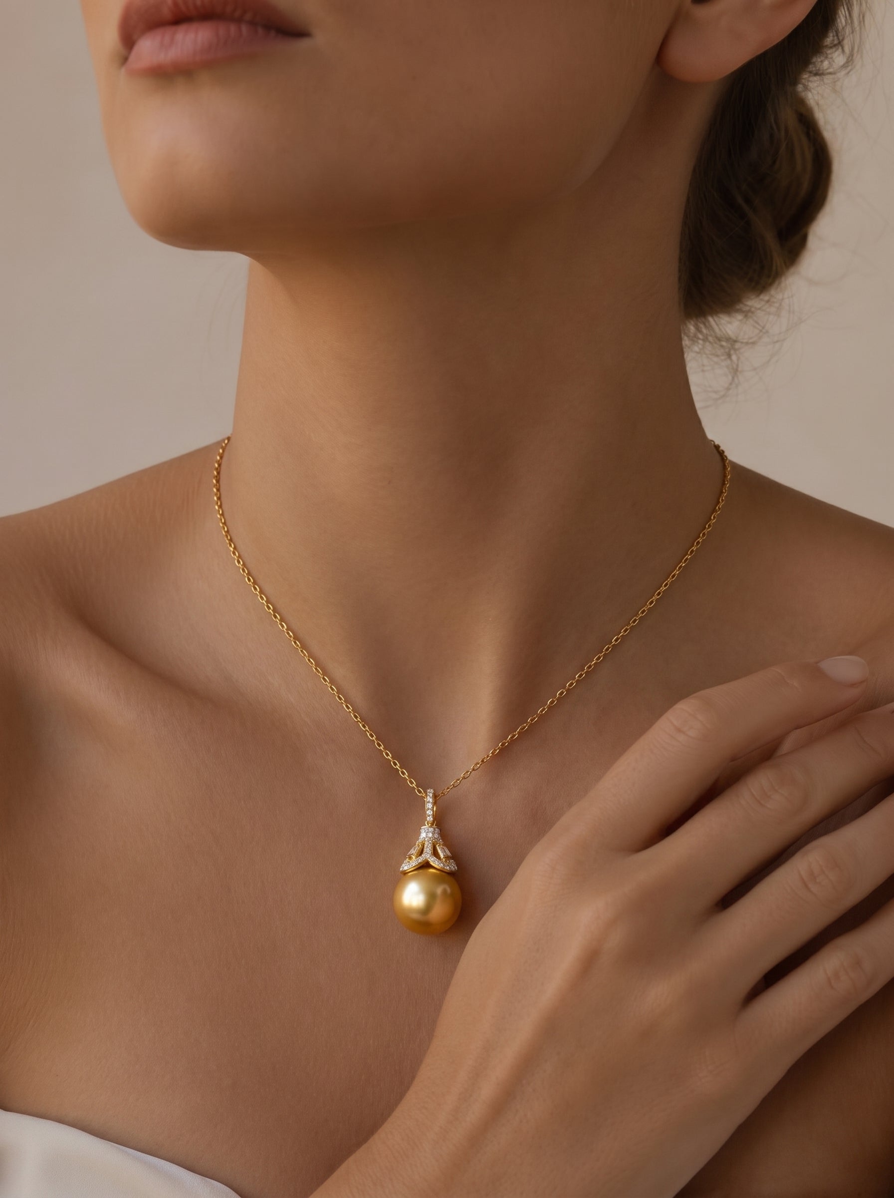 A close-up shot of a model wearing a Regal Glow South Sea Pearl Pendant Necklace, showcasing a large, luminous golden pearl suspended from a cap adorned with diamonds on a delicate gold chain. @model