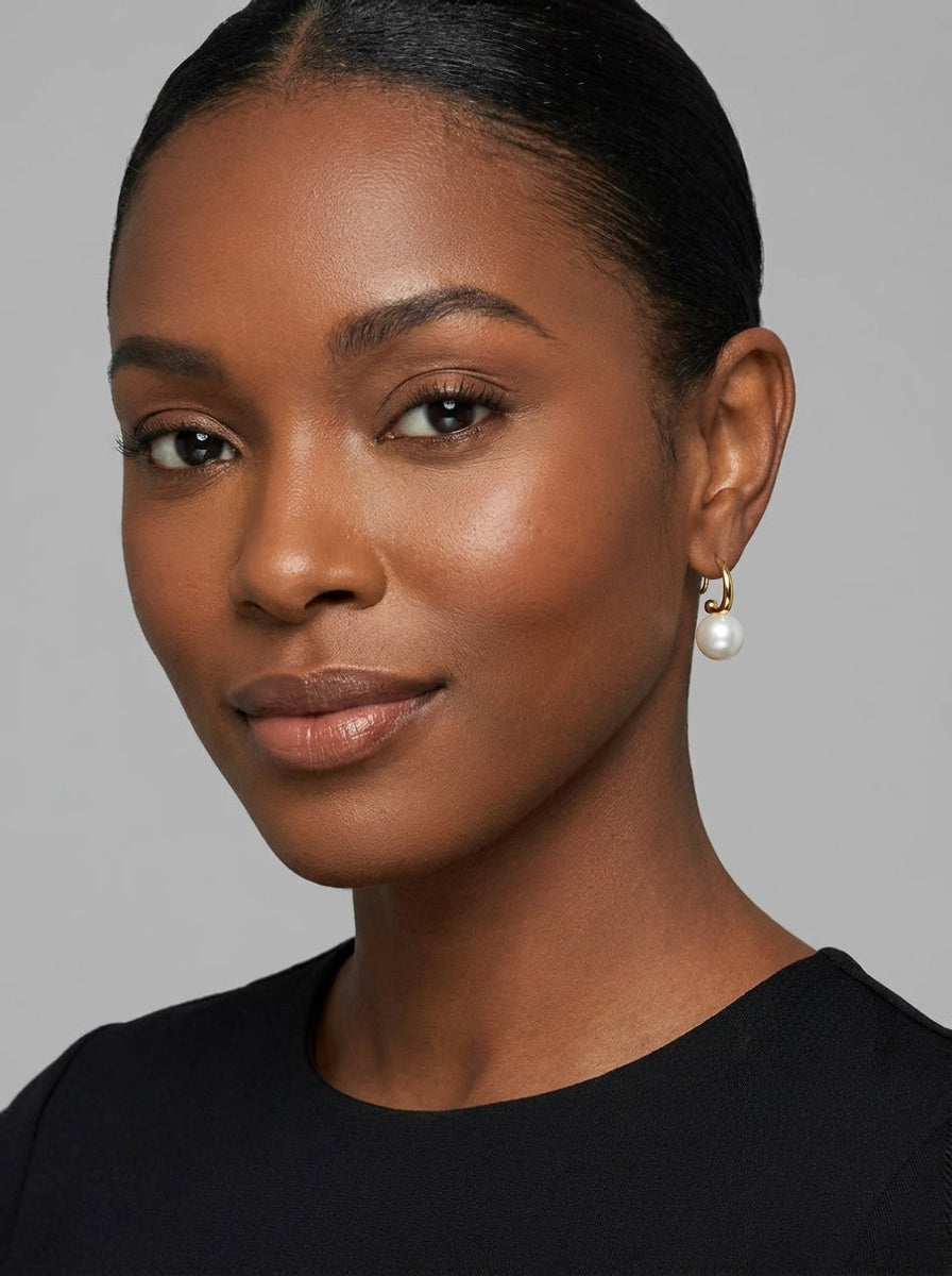 A woman wearing Serene freshwater pearl hook drop earrings made of 18K gold-plated sterling silver, featuring a luminous 10mm round freshwater pearl. @model