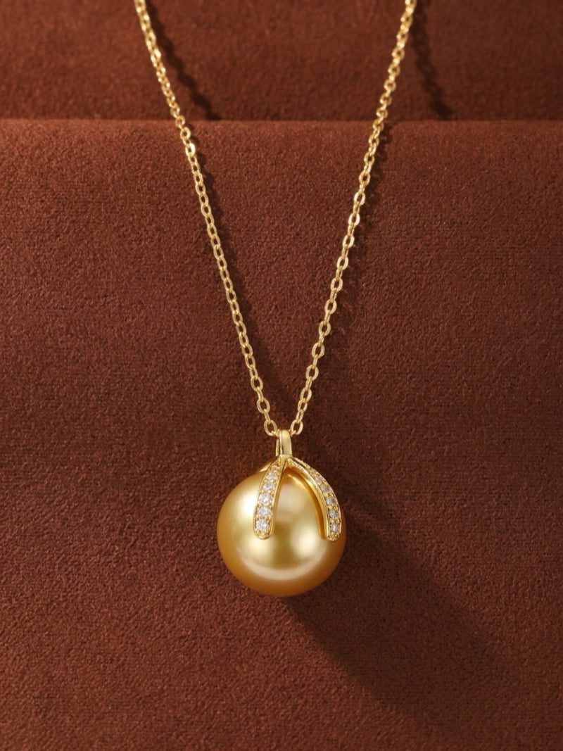 Solara necklace with a large, lustrous 12mm Golden South Sea Pearl pendant, set in a polished gold-tone metal and accented with sparkling gemstones on the bail.
