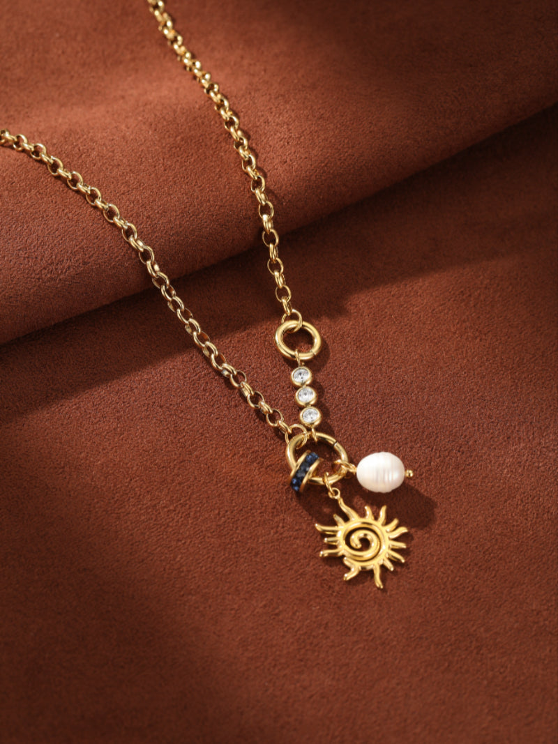 Gold-tone chain necklace with a sun pendant, a white freshwater pearl, and blue accent stones @pearl