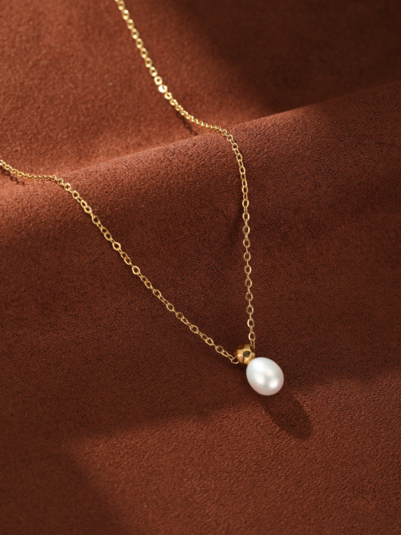 Délicat collier à chaîne ton or présentant une seule et lustrée perle graine blanche d'eau douce avec un capuchon doré facetté unique.