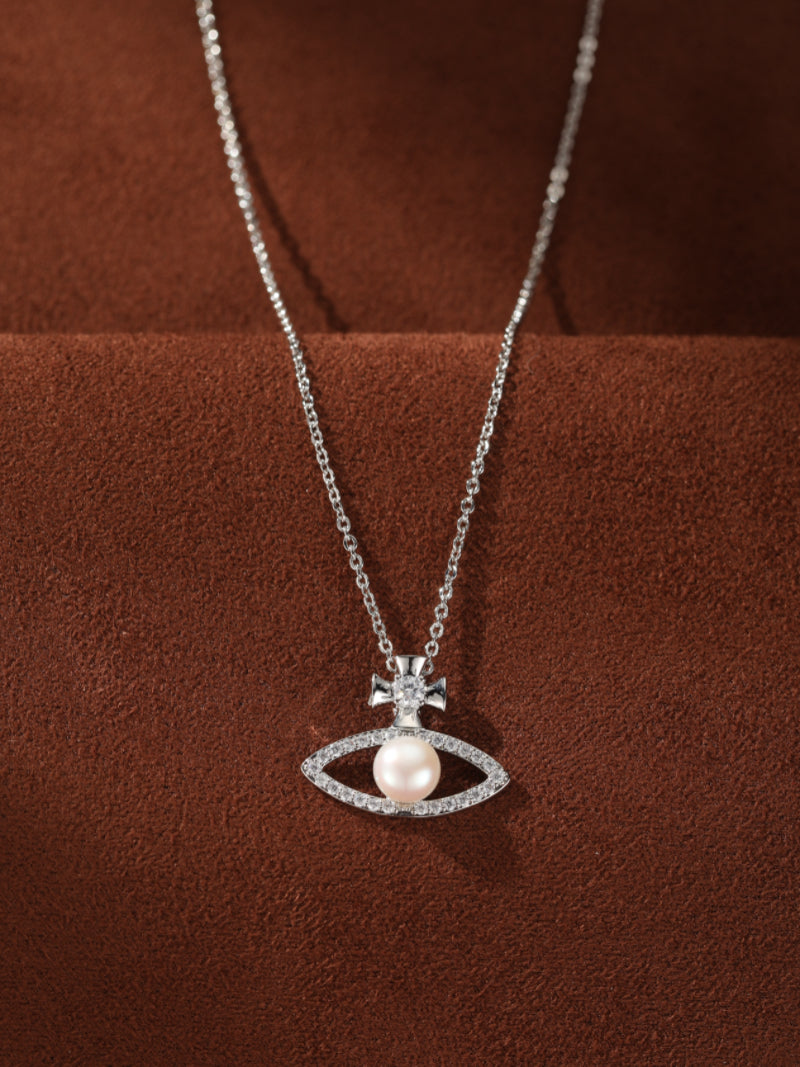 Silver chain pendant necklace featuring an eye-shaped design with a luminous 6mm button freshwater pearl at its center, framed by sparkling accents, and topped with a small cross motif.