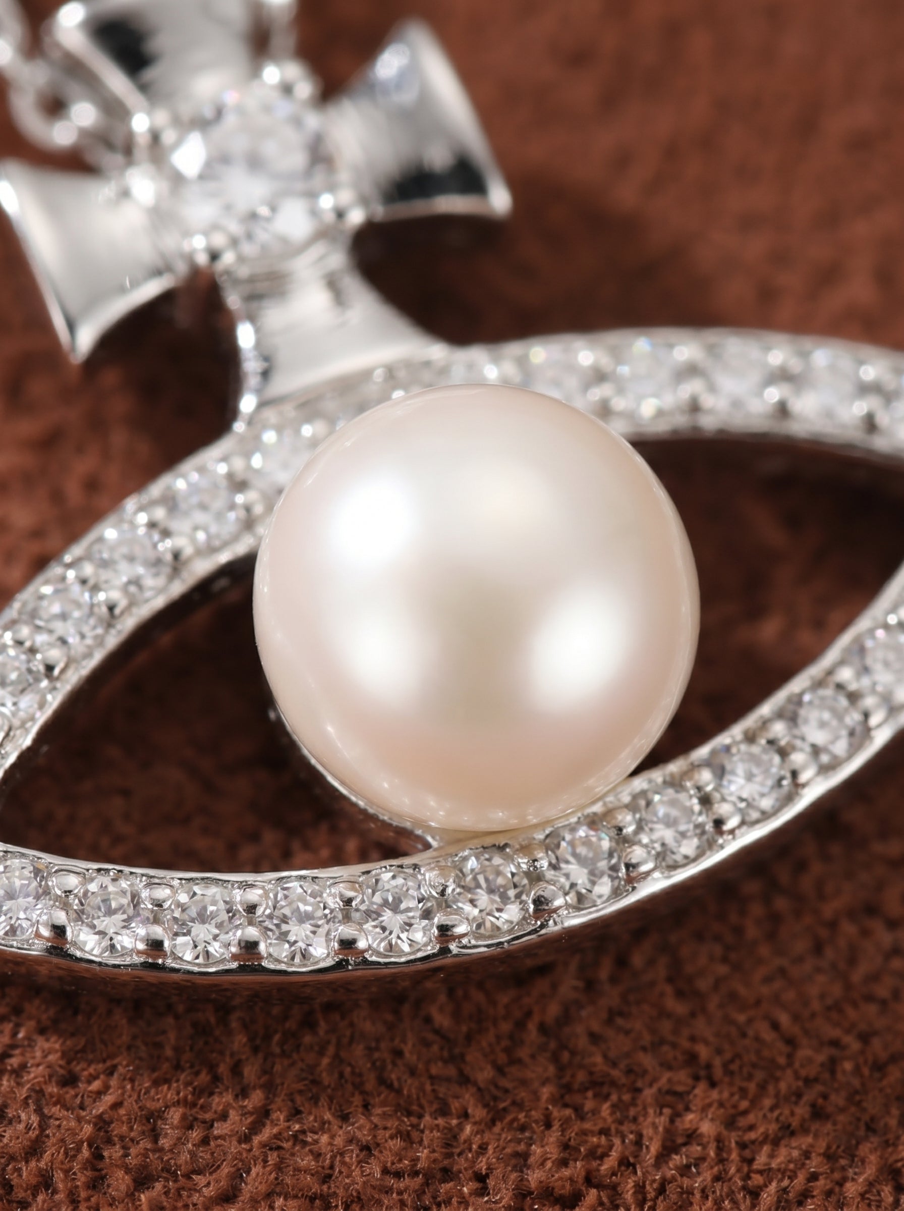 Stellar Gaze necklace featuring an eye-shaped pendant with a white freshwater button pearl at its center, surrounded by sparkling cubic zirconia accents and a small cross detail above, all on a delicate silver chain. Freshwater Pearl Cross Chain Pendant Necklaces@pearl
