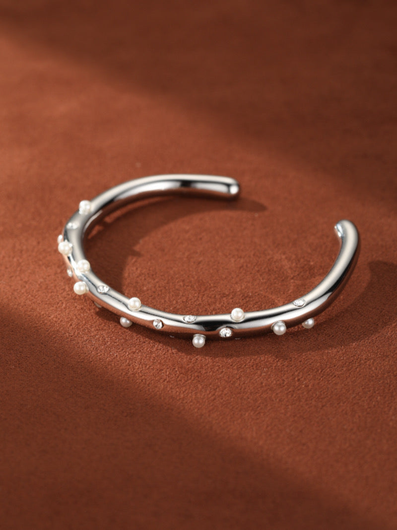 Stellar Path imitation pearl cuff bracelet with sparkling accents on a brown background