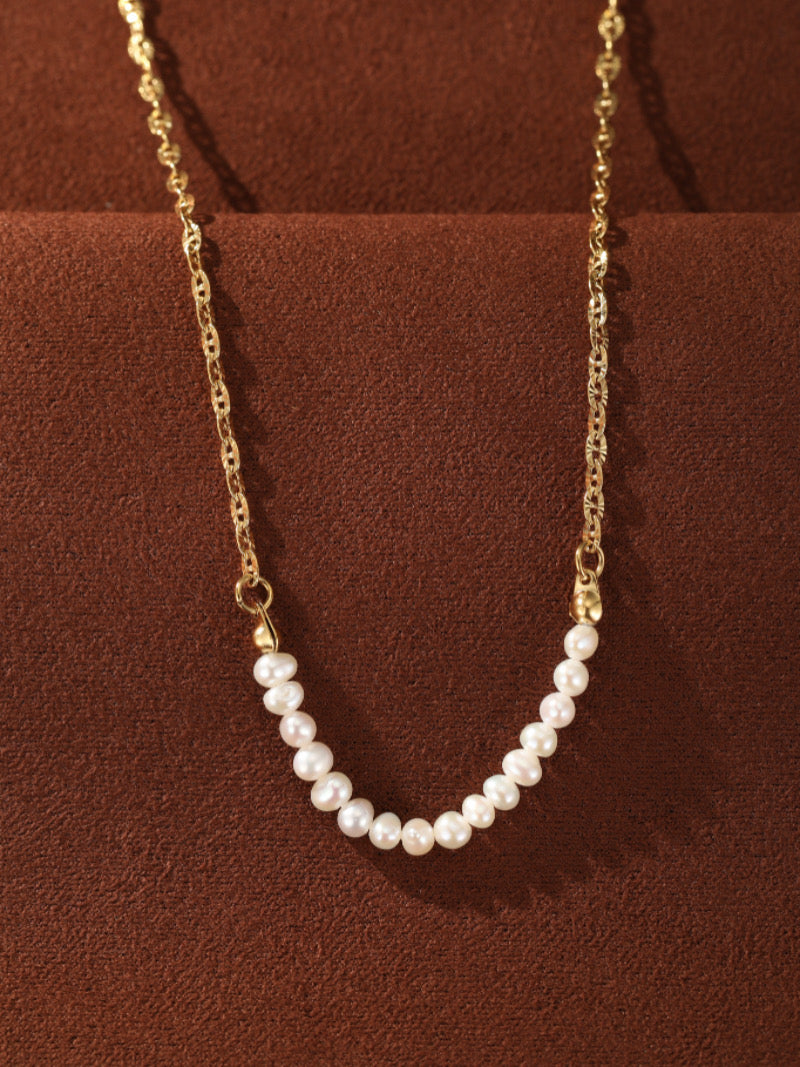 Collier Trace présentant une délicate chaîne ton or avec un subtil arc de petites et lustrées perles blanches d'eau douce en forme bouton.