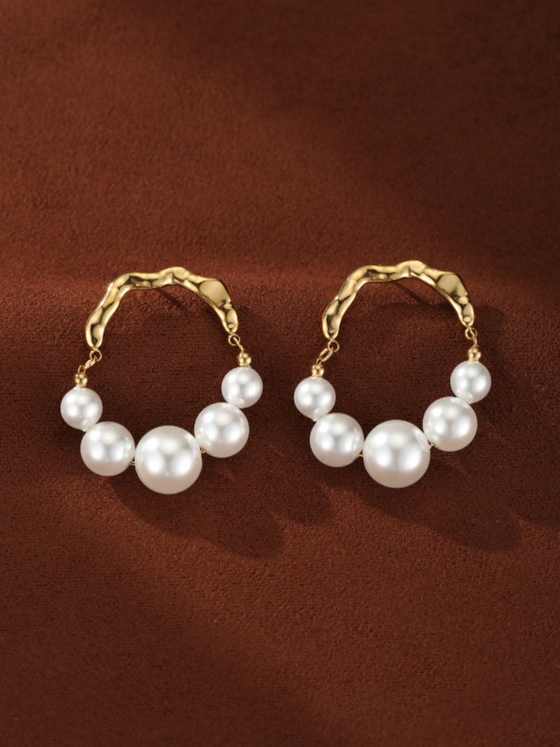 Créoles ondulées en perle d'eau douce Undine présentant un agencement graduel de lustrées perles blanches rondes d'eau douce de 4 mm à 8 mm, bercées par une créole ondulée ton or.