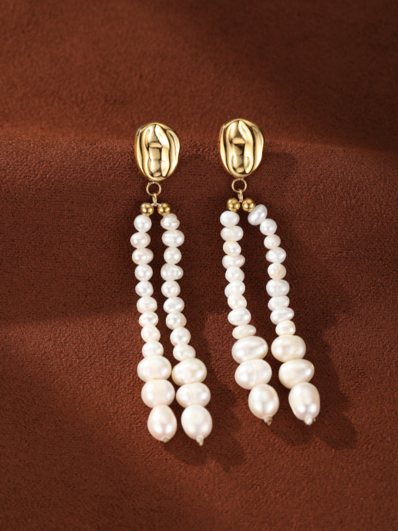 Boucles d'oreilles pendantes Undulate présentant de multiples fils de perles blanches d'eau douce graduelles de 4 mm à 8 mm, suspendues à des puces texturées ton or.