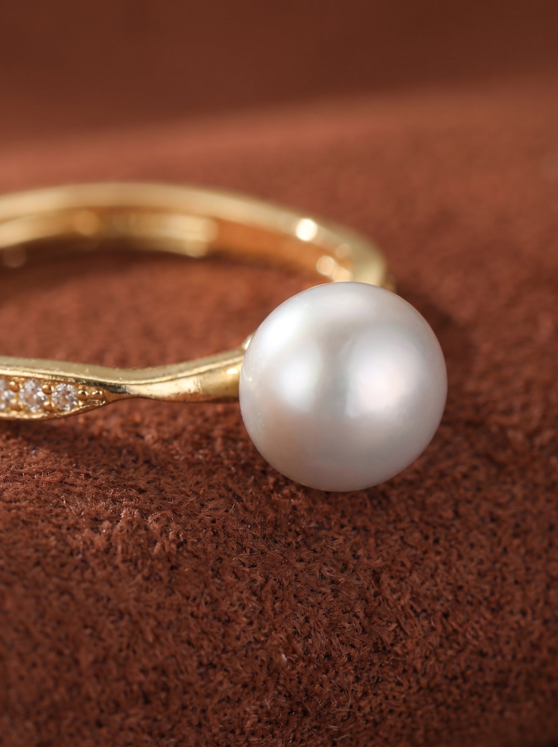 Gold-toned cuff ring with a large freshwater pearl and small accent stones, displaying a modern and elegant design.