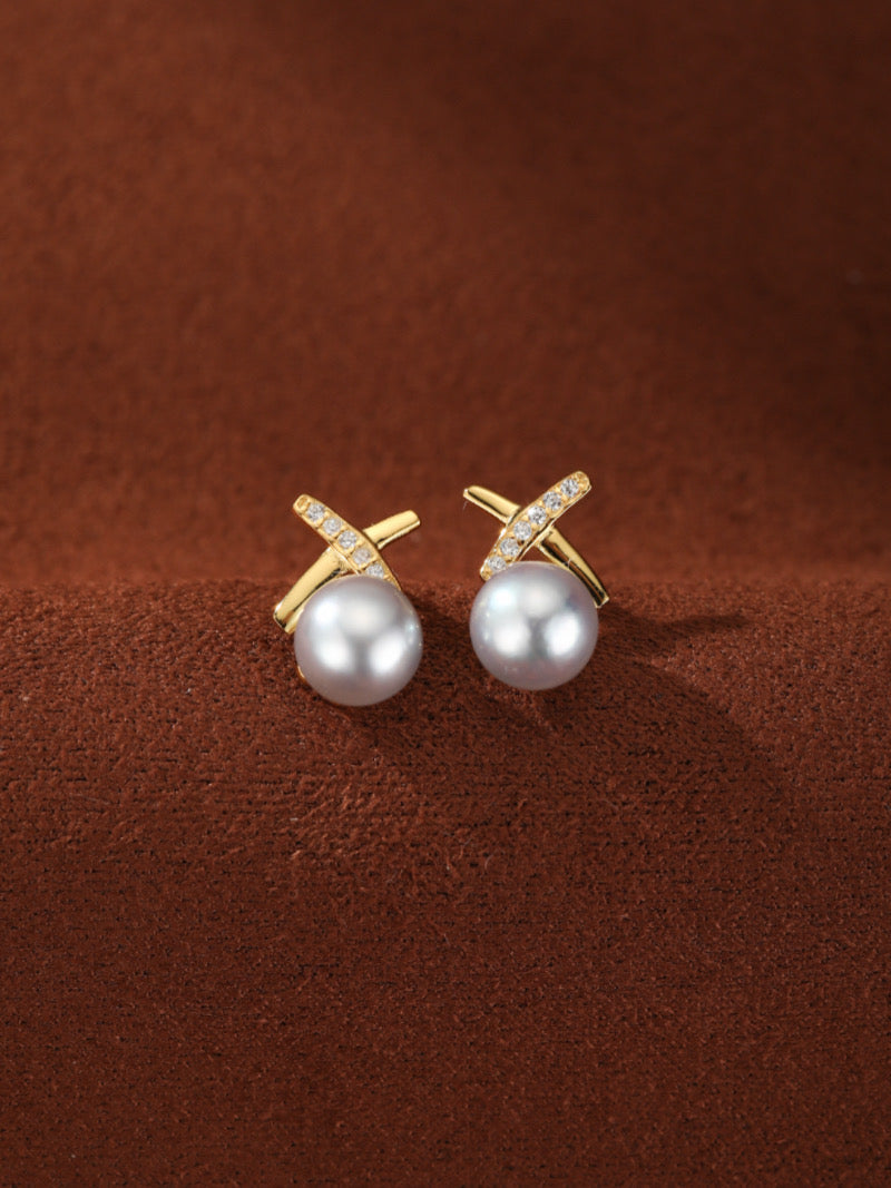 Veritas Akoya Pearl Cross Stud Earrings featuring interlocking gold-toned elements with pavé-set crystals and 8mm Akoya pearls.