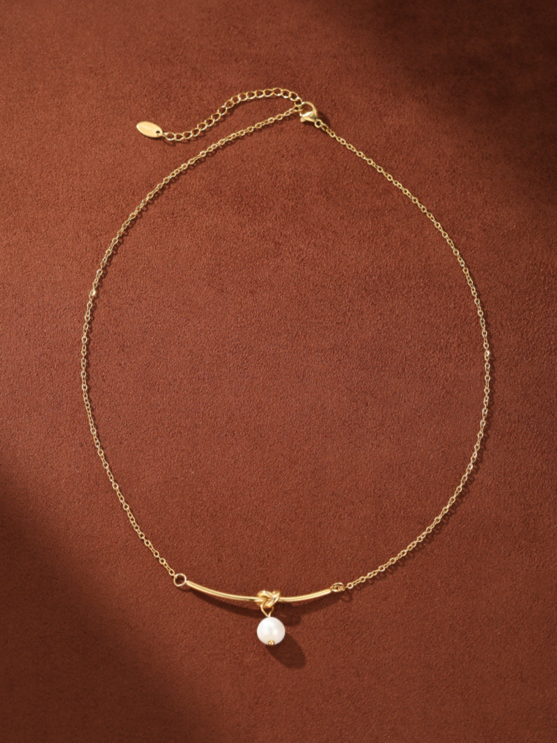 Verve gold chain necklace with a curved bar, knot detail, and a single white freshwater pearl pendant.