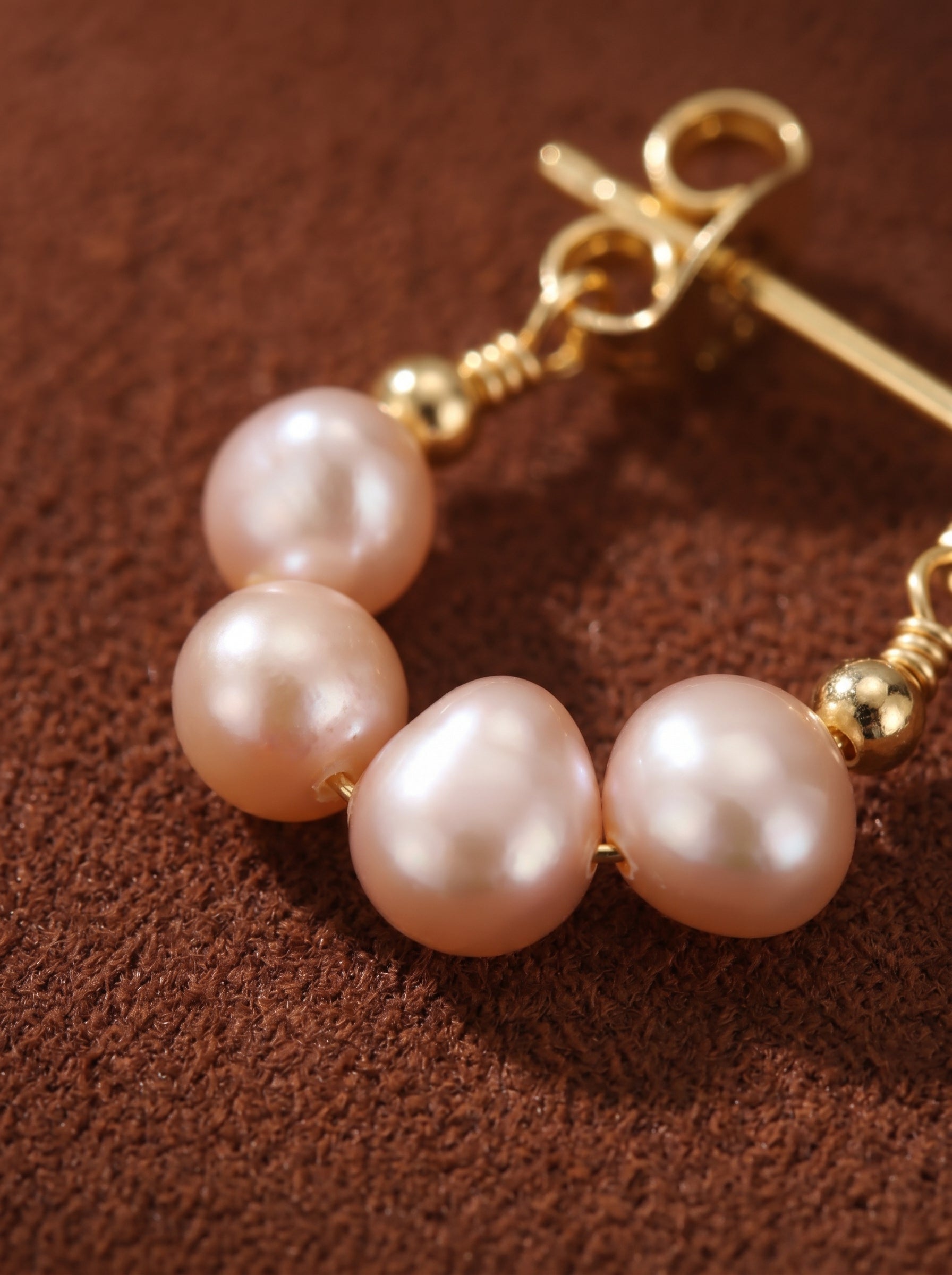 Close-up of Zephyr Freshwater Pearl Hoop Drop Earrings showcasing delicate pink seed pearls on a gold hoop with gold bead accents and a post backing. @pearl